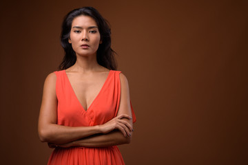 Obraz premium Studio shot of beautiful Asian woman against brown background