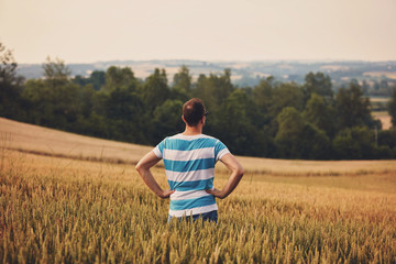 Naklejka na ściany i meble Man enjoying and relaxing in wheat field. Nature concept.