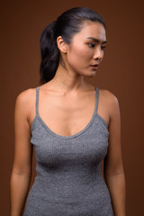 Studio shot of beautiful Asian woman against brown background