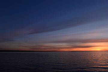 Blue sky in the twilight glow on the horizon over the water of the lake at sunset