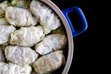 Cabbage Rolls or Dolma. Stuffed cabbage leaves with minced meat, rice, vegetables and herbs in casserole. Isolated on black backround with copy space for your text. Top view. Sarma, golubtsy, golabki