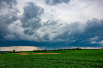 The green fields with the dark, stormy clouds in the background