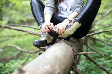 Fototapeta na wymiar women boots and hands with manicure on a tree in the forest