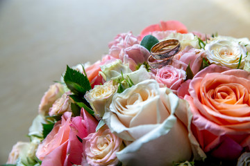 Bouquet of bride with roses and gold wedding rings.