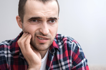 Obraz premium A man has a toothache, grimace from pain, portrait, close up