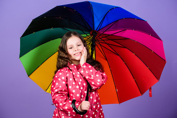 Enjoy rain concept. Kid girl happy hold colorful rainbow umbrella. Rainy weather with proper garments. Bright umbrella. Be rainbow in someones cloud. Rainy day fun. Happy walk under umbrella