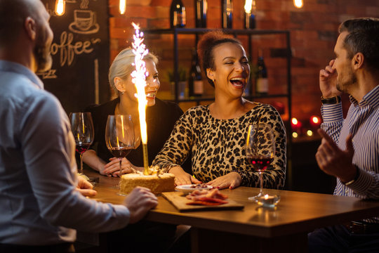 Group of friends celebrating birthday in a cafe behind bar counter
