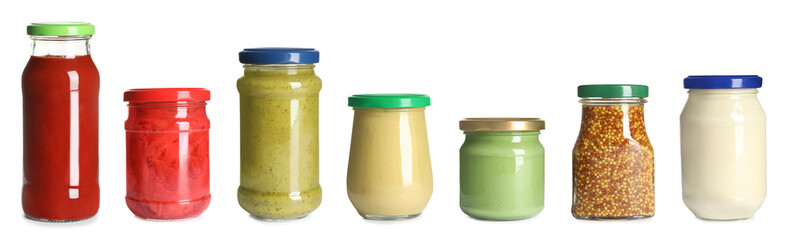 Set of glass jars with different delicious sauces on white background