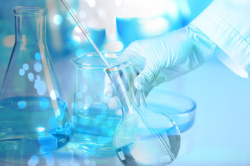 Scientist holding glass flask with liquid, closeup. Experimental chemistry