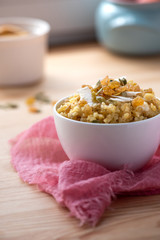 Cooked bulgur with raisins, seeds and coconut in a white bowl on a wooden table. Sweet bulgur porridge, vegetarian food.
