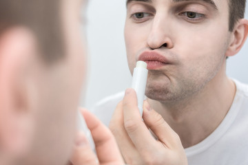 White metrosexual, man holding lipstick, in his hand close to face