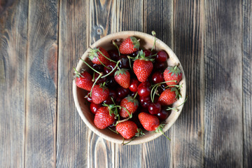 Strawberries and cherries in a brown wooden bowl. Fresh organic summer berries