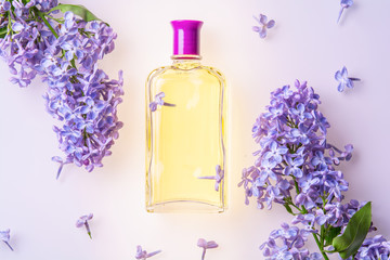 Obraz na płótnie Canvas bottle of yellow perfume with lilac flowers on white background
