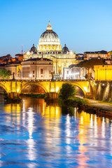 Fototapeta premium St Peters Basilica in Vatican and Ponte Sant'Angelo Bridge over Tiber River at dusk. Romantic evening cityscape of Rome, Italy