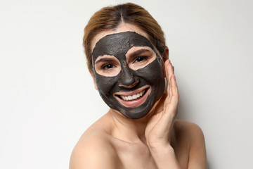 Beautiful woman with black mask on face against light background