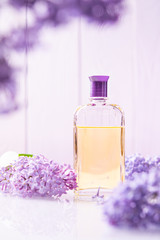 Obraz na płótnie Canvas bottle of yellow perfume with lilac flowers on white background