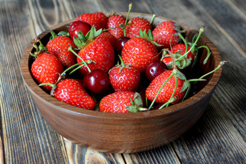 Strawberries and cherries in a brown wooden bowl. Fresh organic summer berries