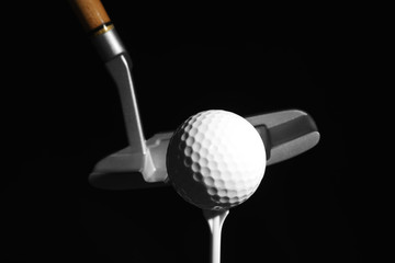 Golf club and ball against dark background
