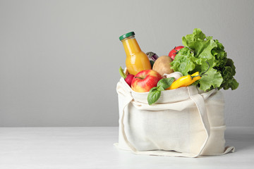 Fototapeta Cloth bag with vegetables and bottle of juice on table against grey background. Space for text obraz