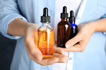 Woman holding different bottles with essential oils, closeup