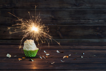 birthday cake with sparkler on old wooden background