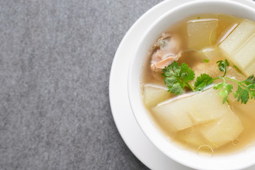 Boiled winter melon soup with chicken rib in white bowl on table.