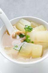 Boiled winter melon soup with chicken rib in white bowl on table.