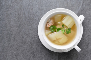 Boiled winter melon soup with chicken rib in white bowl on table.