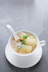 Boiled winter melon soup with chicken rib in white bowl on table.