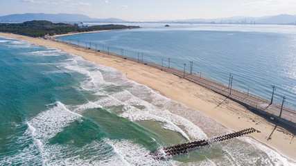 Tombolo and waves at Shikanoshima Island aerial footage over Shikanoshima bridge