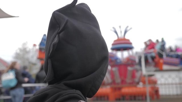 Little boy against a ferris wheel in amusement park.