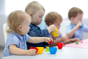 babies group learning arts and crafts in playroom with interest