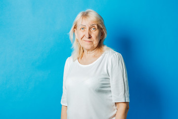 Old woman in white t-shirt over blue background