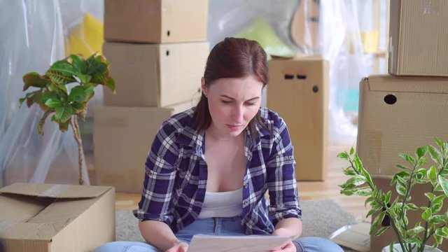 portrait tired young woman among the boxes to move,reads the Eviction Order Document money problem
