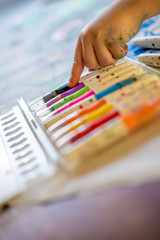 Childs hand pointing at colourful pens