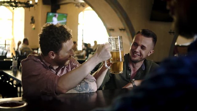 Cheerful friends drinking draft beer in a pub