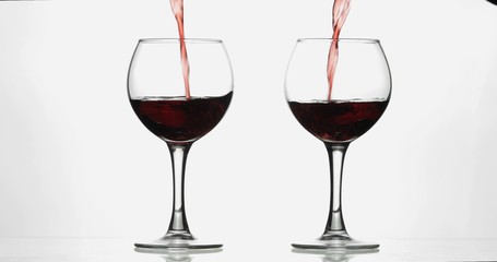 Rose wine. Red wine pour in two wine glasses over white background