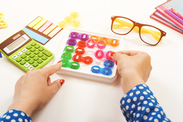 Woman playing game at work desk. The concept of concentration, logical thinking. Workplace table with calculator, pens, female glasses and notebooks. Modern logic games.
