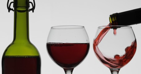 Rose wine. Red wine pour in wine glass over white background