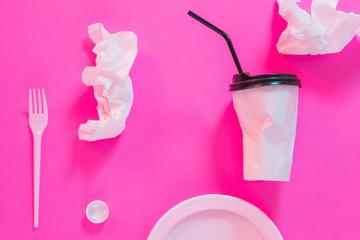 Earth pollution. Plastic littering. Disposable tableware over magenta background.