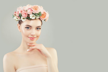 Cheerful young woman with clear skin and flowers on white background