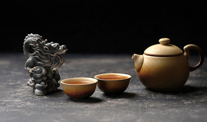 tea ceremony - Chinese dragon, ceramic teapot and cups. Asian culture cuisine concept. Beautiful tea ceremony with dragon statue on blurred dark background. copy space, soft focus