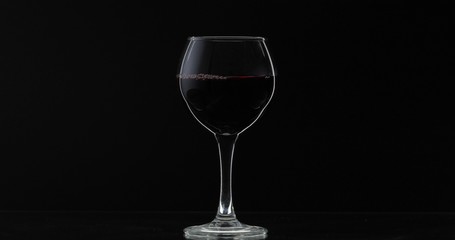 Rose wine. Red wine in wine glass over black background. Silhouette