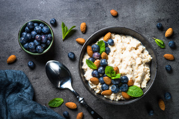 Oatmeal porridge with fresh berries and nuts top view.  - obrazy, fototapety, plakaty