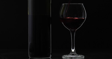 Rose wine. Red wine pour in wine glass over black background. Silhouette