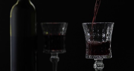 Rose wine. Red wine pour in wine glass over black background. Silhouette