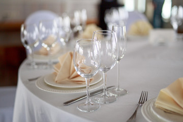 table setting, glasses are on the table, napkins in napkins beige, appliances fork knife, white clean plates, the table is set before the event