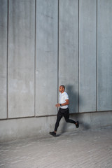 Man running in the urban space with  concrete wall on background