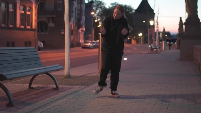 young woman dancing on sidewalk at evening