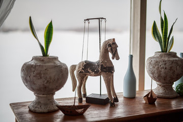 Fototapeta na wymiar wooden horse vintage, a pot with a flower stands on the windowsill near the window in winter